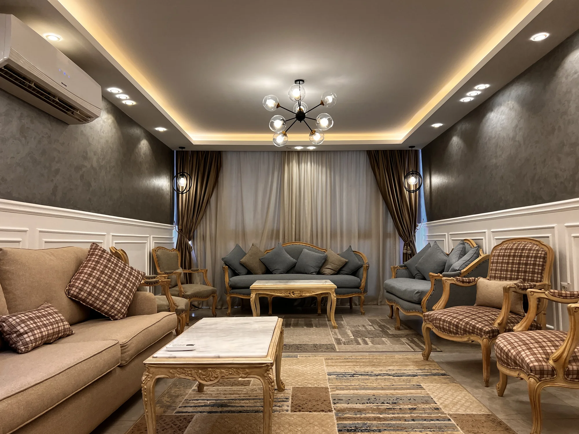 A 155 sqm apartment with grey seating, warm lighting and a connected living and dining room.